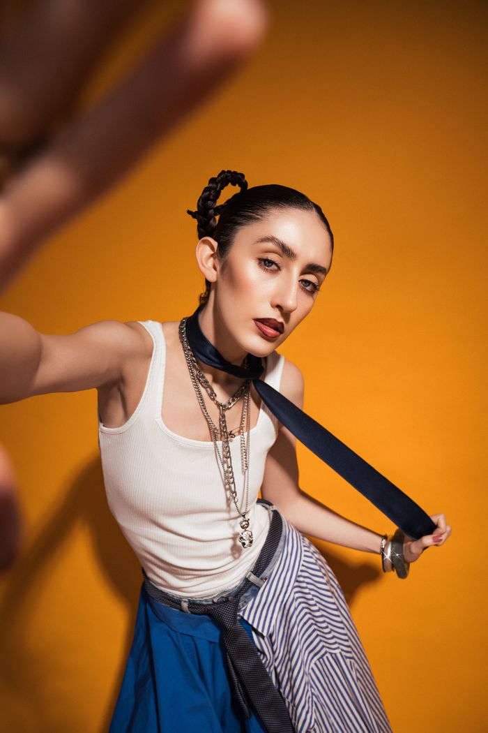 Stylish portrait of an adult woman with bold accessories against a vibrant yellow backdrop, showcasing modern fashion.