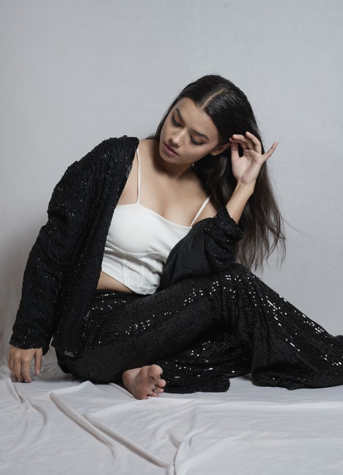 Stylish fashion model in black sequined clothing posing indoors for a portrait shoot.