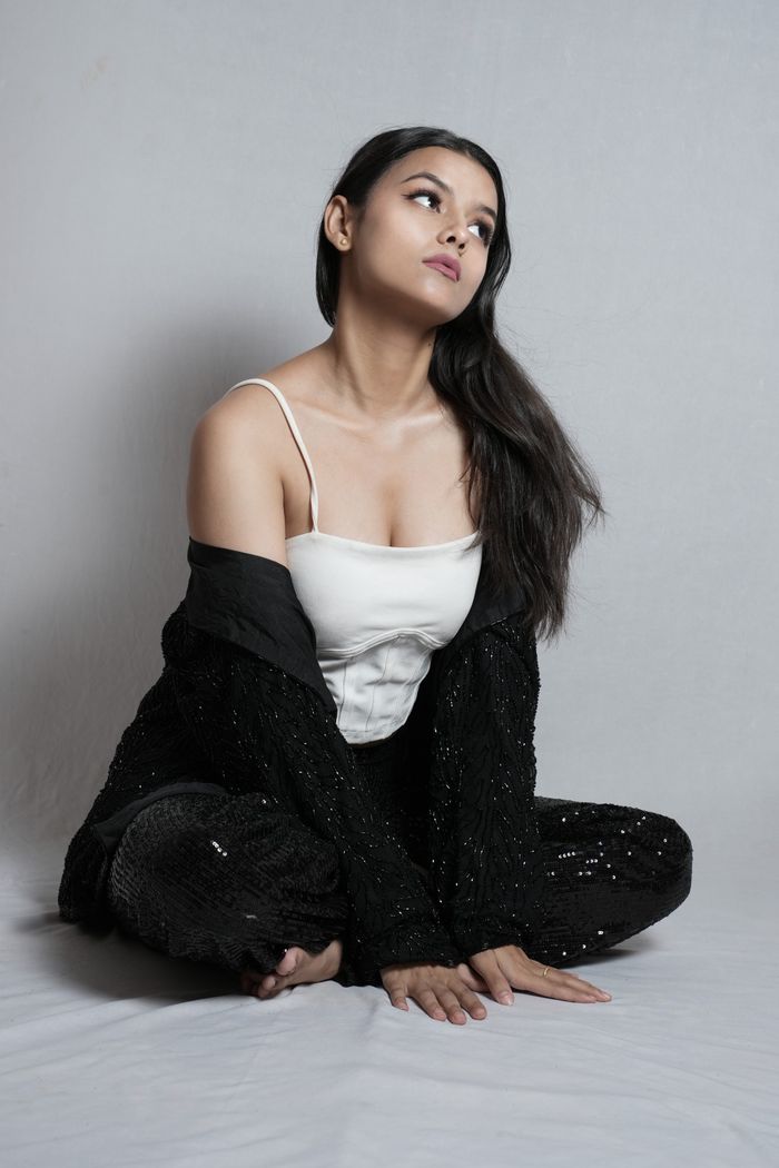 Indian woman posing in a stylish outfit during a fashion photoshoot against a neutral background.